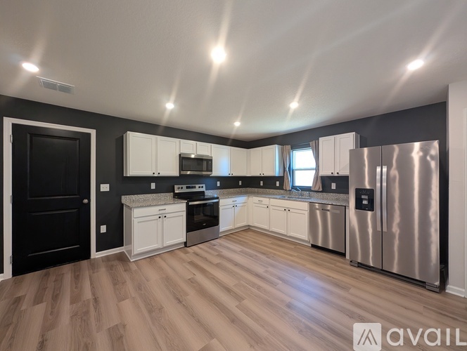 A kitchen with white cabinets and a stainless steel refrigerator.