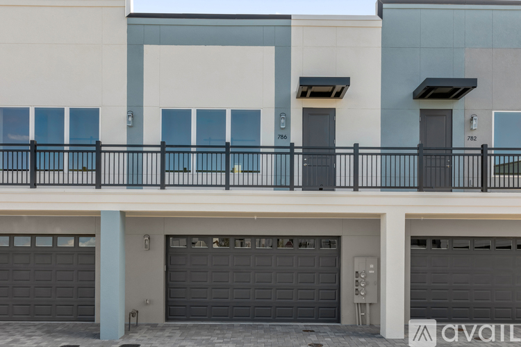A modern building with a balcony and garage doors.