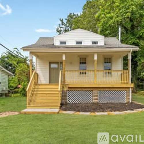 A small white house with a wooden porch and stairs leading up to the front door.