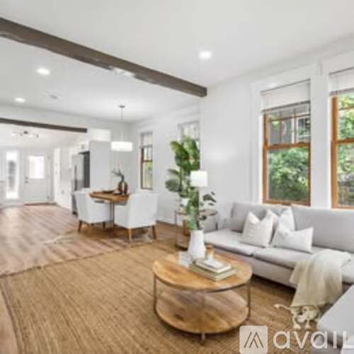 A living room with a white couch, a wooden coffee table, and a large window.