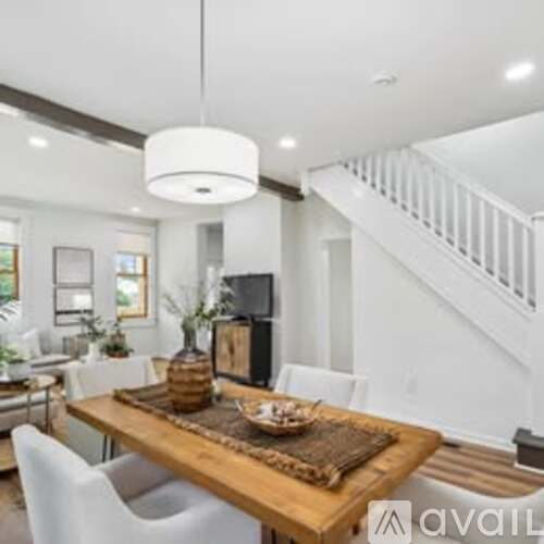 A modern dining room with a wooden table and white chairs.