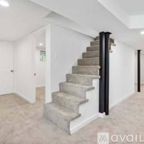 A staircase with a black railing leads up to a white door.