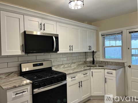 A kitchen with white cabinets and a black microwave.