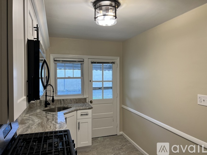 A kitchen with a sink, window, and cabinets.