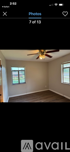 A room with a ceiling fan and two windows.