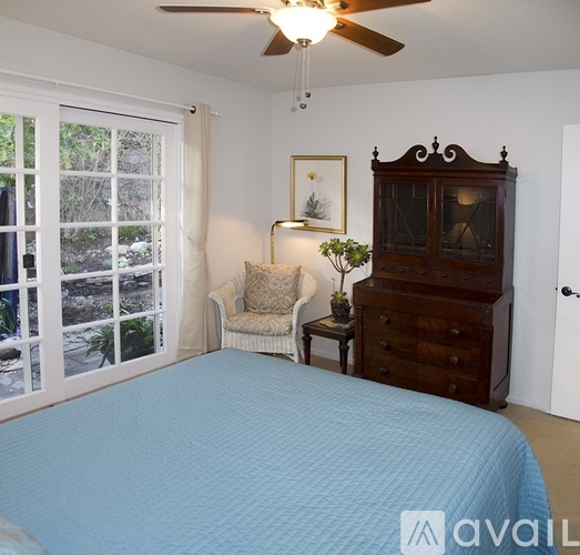 A bedroom with a bed, chair, and cabinet.