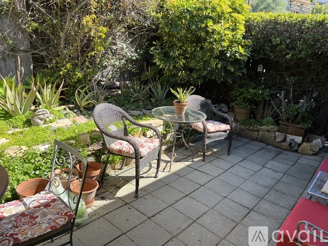 A patio with a table and chairs surrounded by greenery.