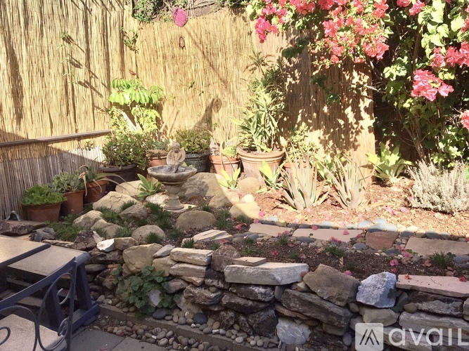 A garden with a stone wall and a bench.