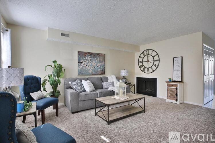 A living room with a grey couch, a blue chair, and a fireplace.