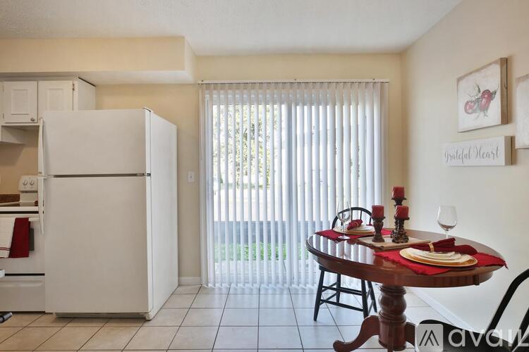 A kitchen with a table set for two with a view of the backyard.