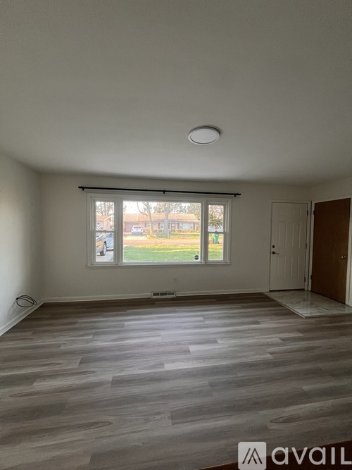 A room with a large window and wooden flooring.