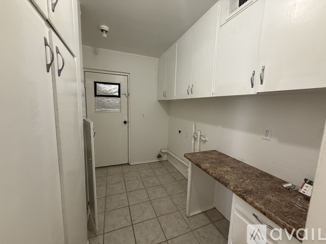 A kitchen with white cabinets and a granite counter.