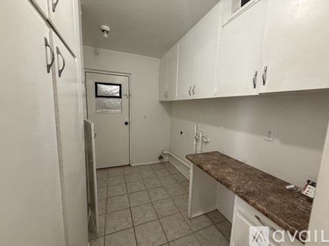A kitchen with white cabinets and a granite counter.