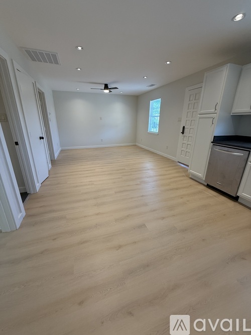A spacious kitchen with wooden flooring and white cabinetry.