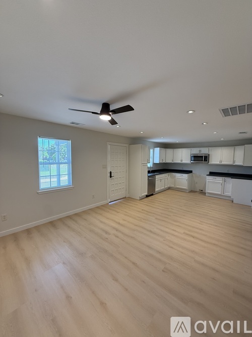 A spacious room with wooden flooring and a ceiling fan.