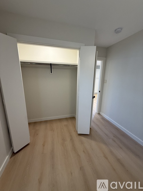 A room with a white door and a wooden floor.
