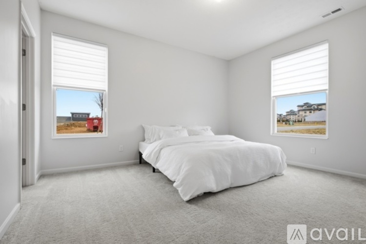 A bedroom with a large bed and two windows with blinds.