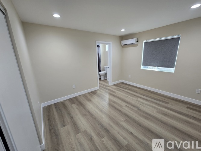 A room with wooden flooring and a window with blinds.