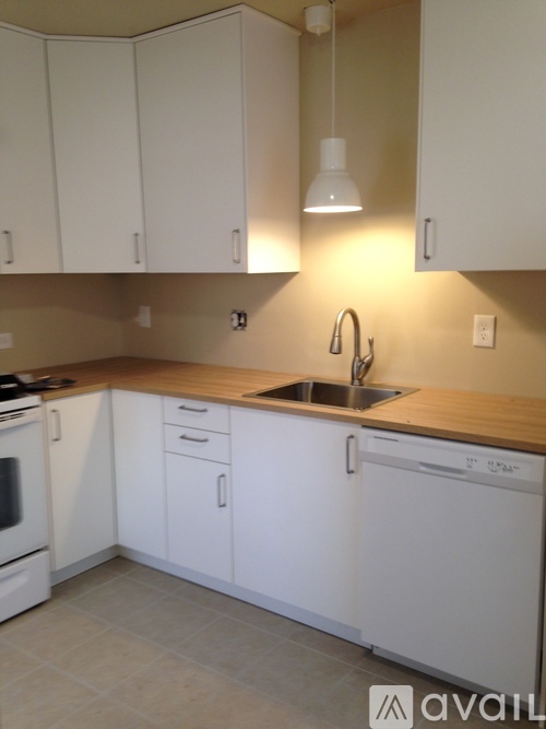 A kitchen with white cabinets and a wooden countertop.