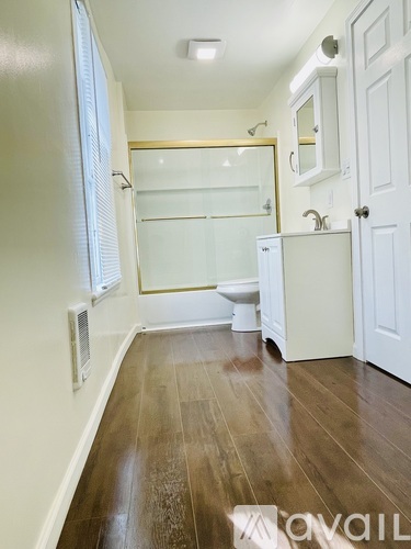 A bathroom with a toilet, sink, and mirror.