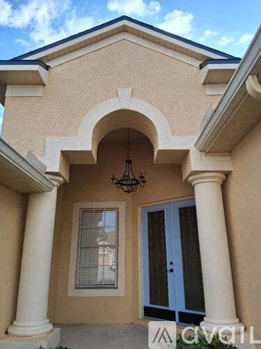 A house with a blue door and a chandelier hanging from the arch.