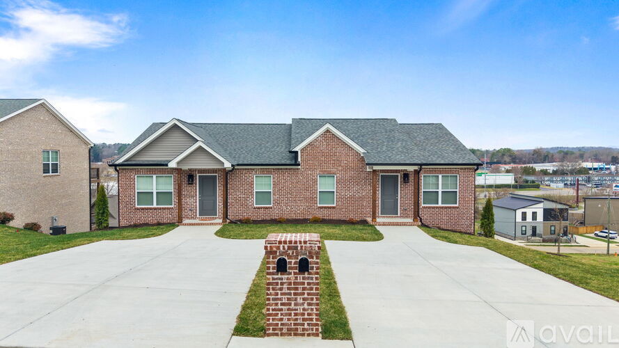 A brick house with a grey roof and a green lawn in front.