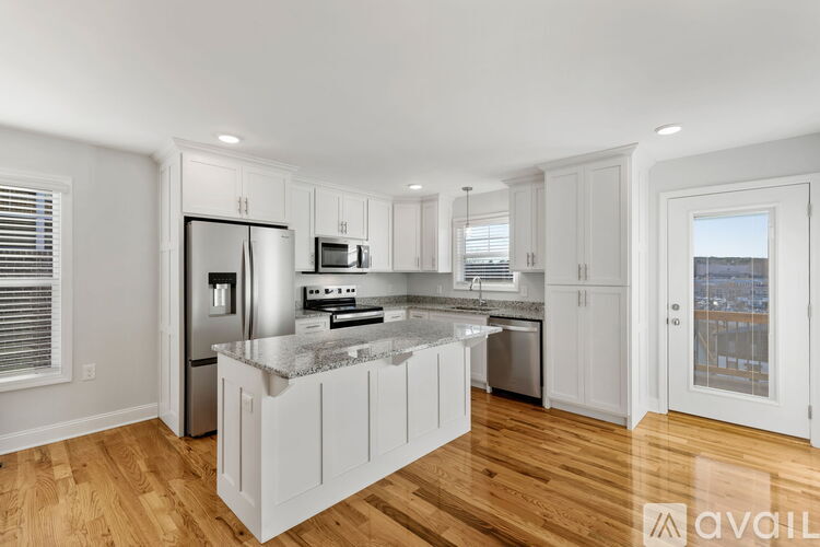 A kitchen with white cabinets and a marble countertop.