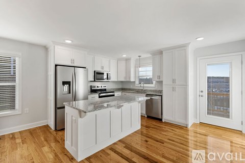 A kitchen with white cabinets and a marble countertop.