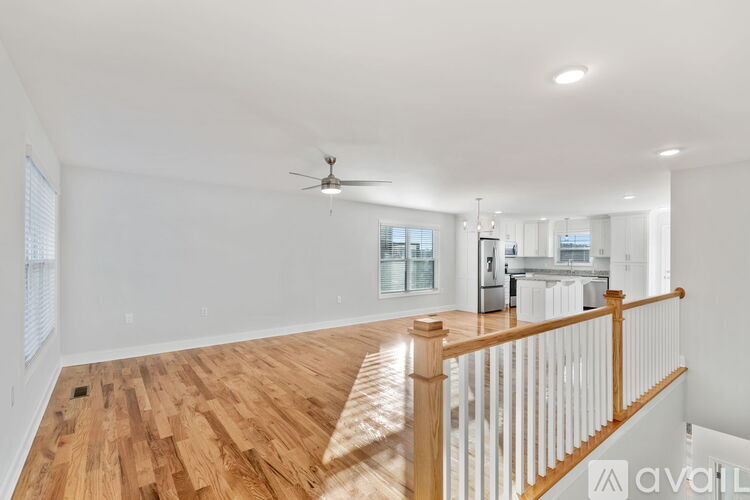 A spacious room with wooden flooring and a ceiling fan.