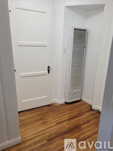 A white door with a black handle is in a room with wooden floors.