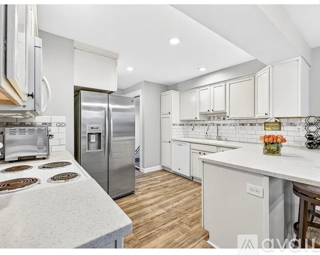 A modern kitchen with a stainless steel refrigerator and a white countertop.
