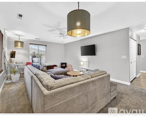 A living room with a large couch and a flat screen TV mounted on the wall.