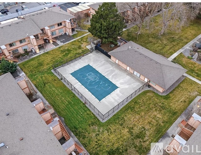 A swimming pool surrounded by a concrete fence and a grassy area.