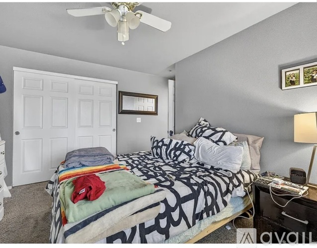 A bedroom with a bed, dresser, and a ceiling fan.
