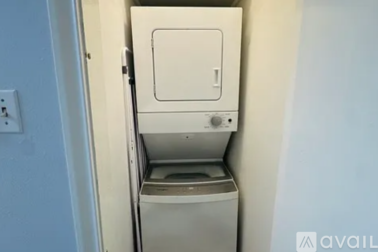 A small white dryer is in a narrow space.
