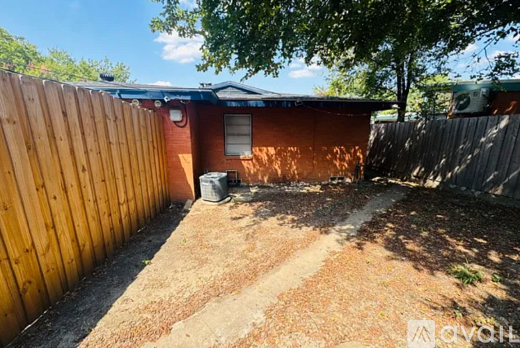 A backyard with a wooden fence and a red building in the background.