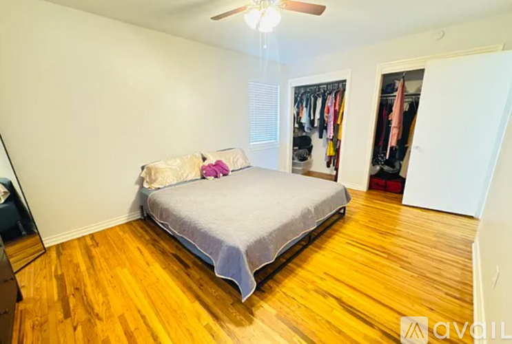A bedroom with a bed, a closet, and a ceiling fan.