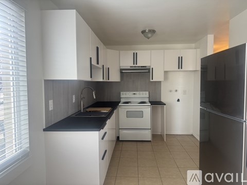 A kitchen with white cabinets and black countertops.