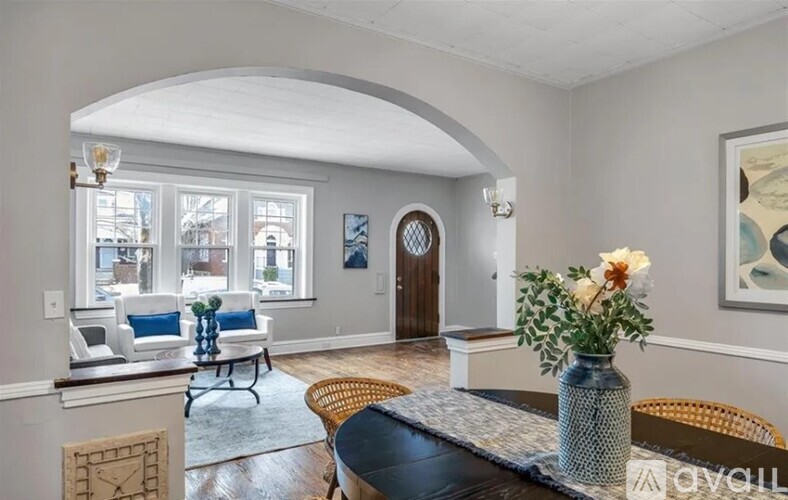A living room with a couch, a chair, a table, and a vase of flowers.