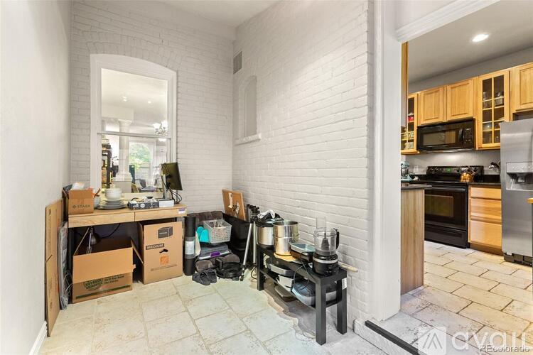 A kitchen with a white brick wall and wooden cabinets.