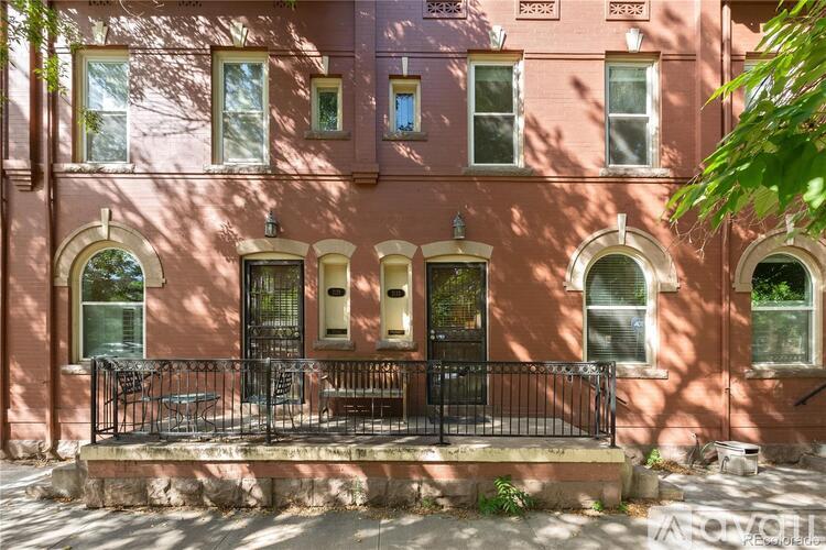 A pink building with a black iron fence and a small garden in front.