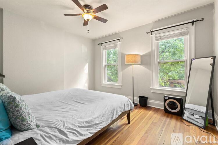 A bedroom with a bed, a ceiling fan, and a window with a view of trees.
