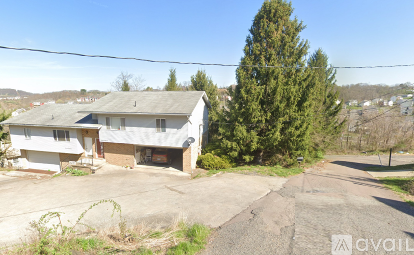 A house with a driveway and a tree in front.