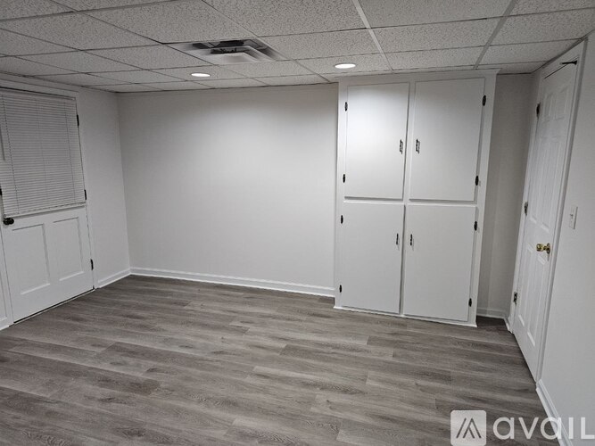 A room with white walls and wooden flooring with a logo on the bottom right.