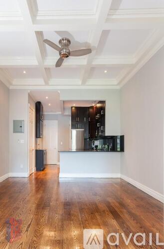 A spacious room with a wooden floor and a ceiling fan.