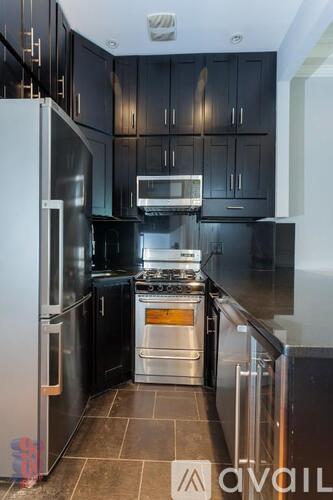 A modern kitchen with black cabinets and stainless steel appliances.