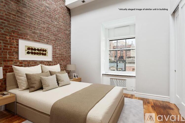 A bedroom with a brick wall and a bed with a white comforter.