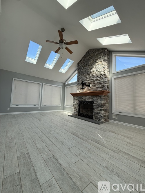 A spacious room with a stone fireplace and skylights.