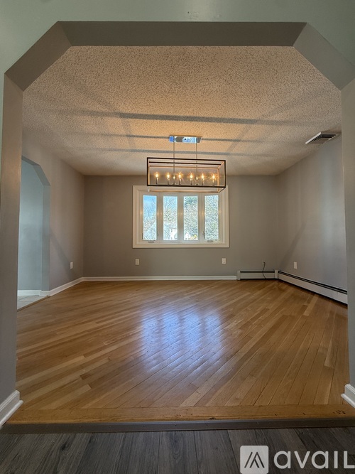 A room with wooden floors and a window with a view of trees outside.