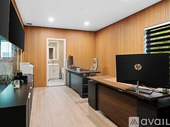 A modern office space with a wooden panelled wall and a black HP monitor on a wooden desk.